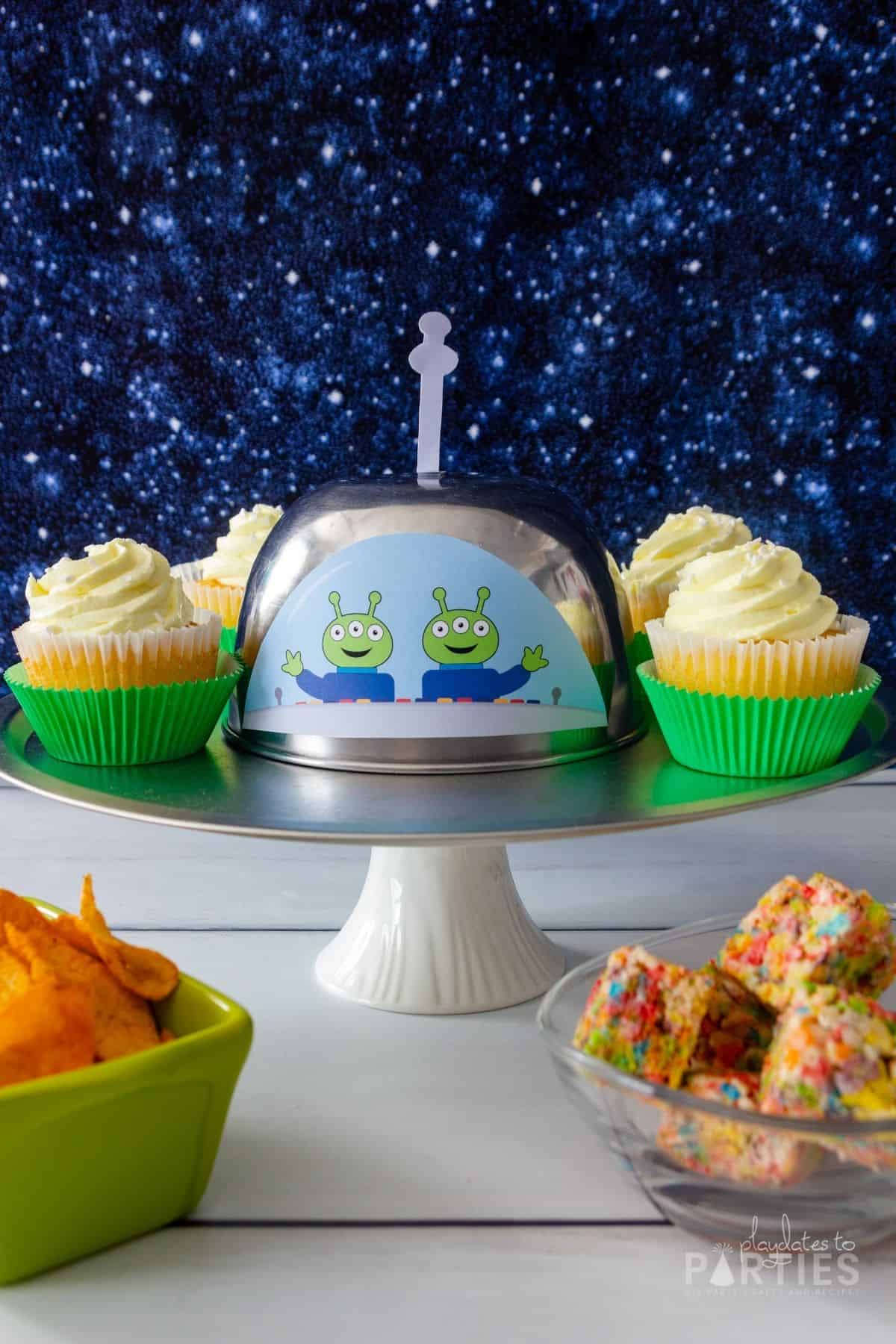 Front view of a UFO party platter with cute aliens waving hello.