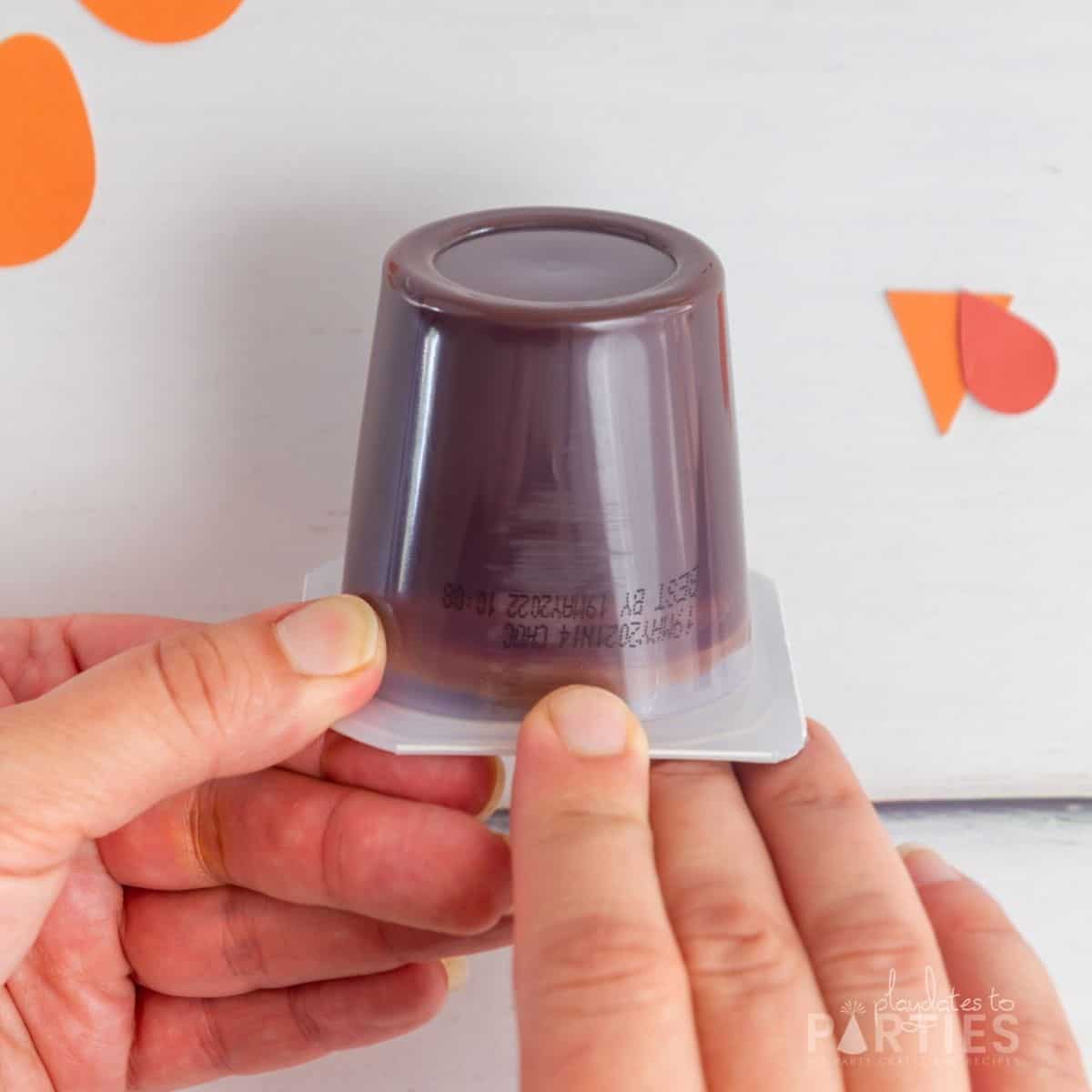 A woman's hand pointing to printed information on a pudding cup.
