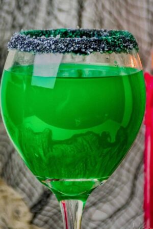 Front view of a large wine glass filled with a green Halloween cocktail.