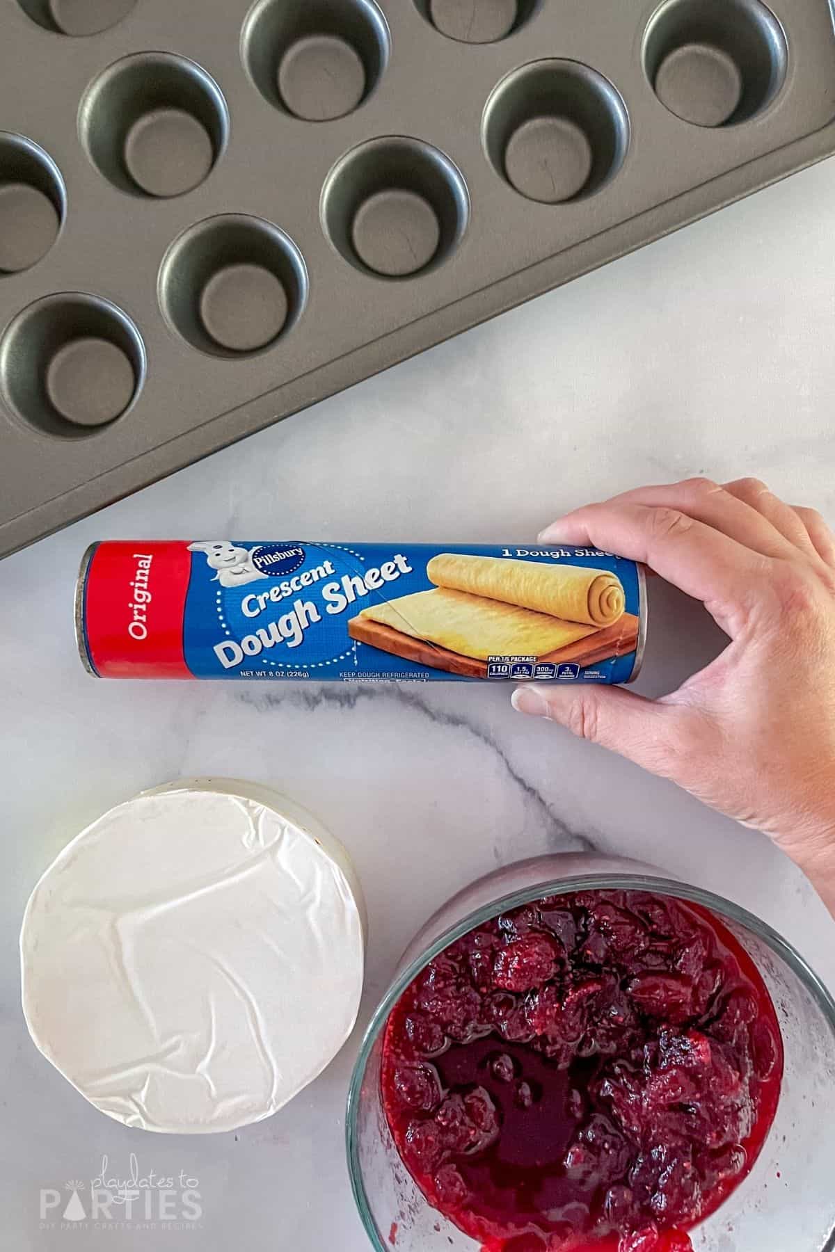 Ingredients for cranberry brie bites: cranberry sauce, brie, and crescent dough sheets.