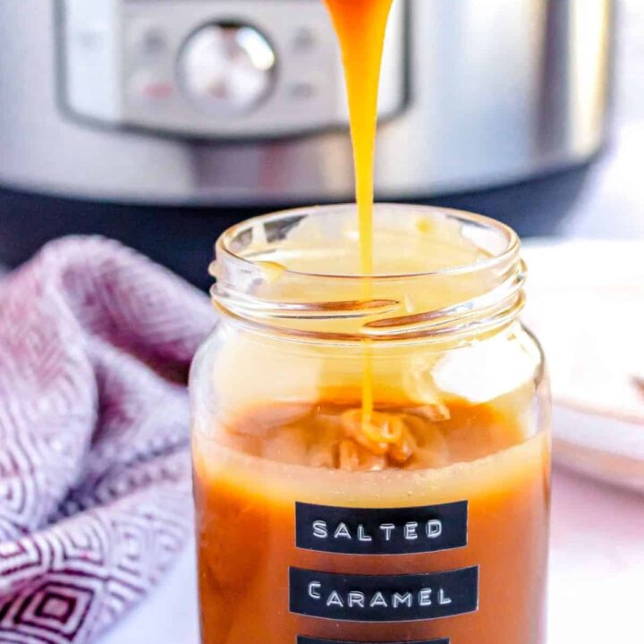 A drizzle of caramel sauce from a spoon being pulled out of a jar.