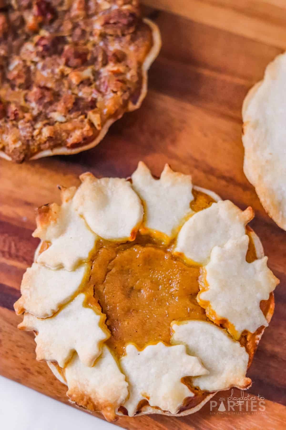 Close up view of a mini pumpkin pie decorated with pie crust leaves and acorns.