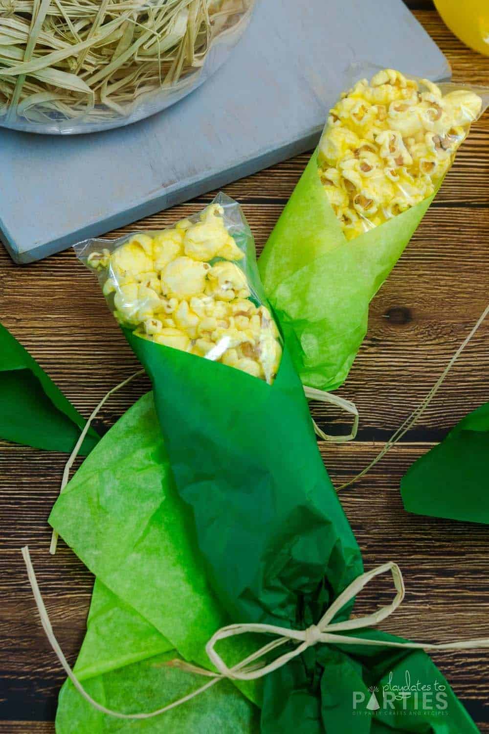 Two popcorn corn on the cob favors with different shades of green tissue paper.