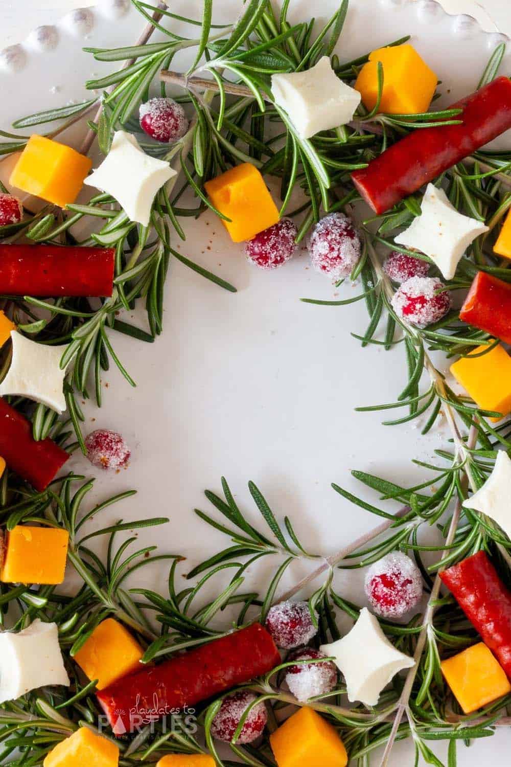 Close up of a rosemary wreath with candied cranberries, cheese, and sausage.
