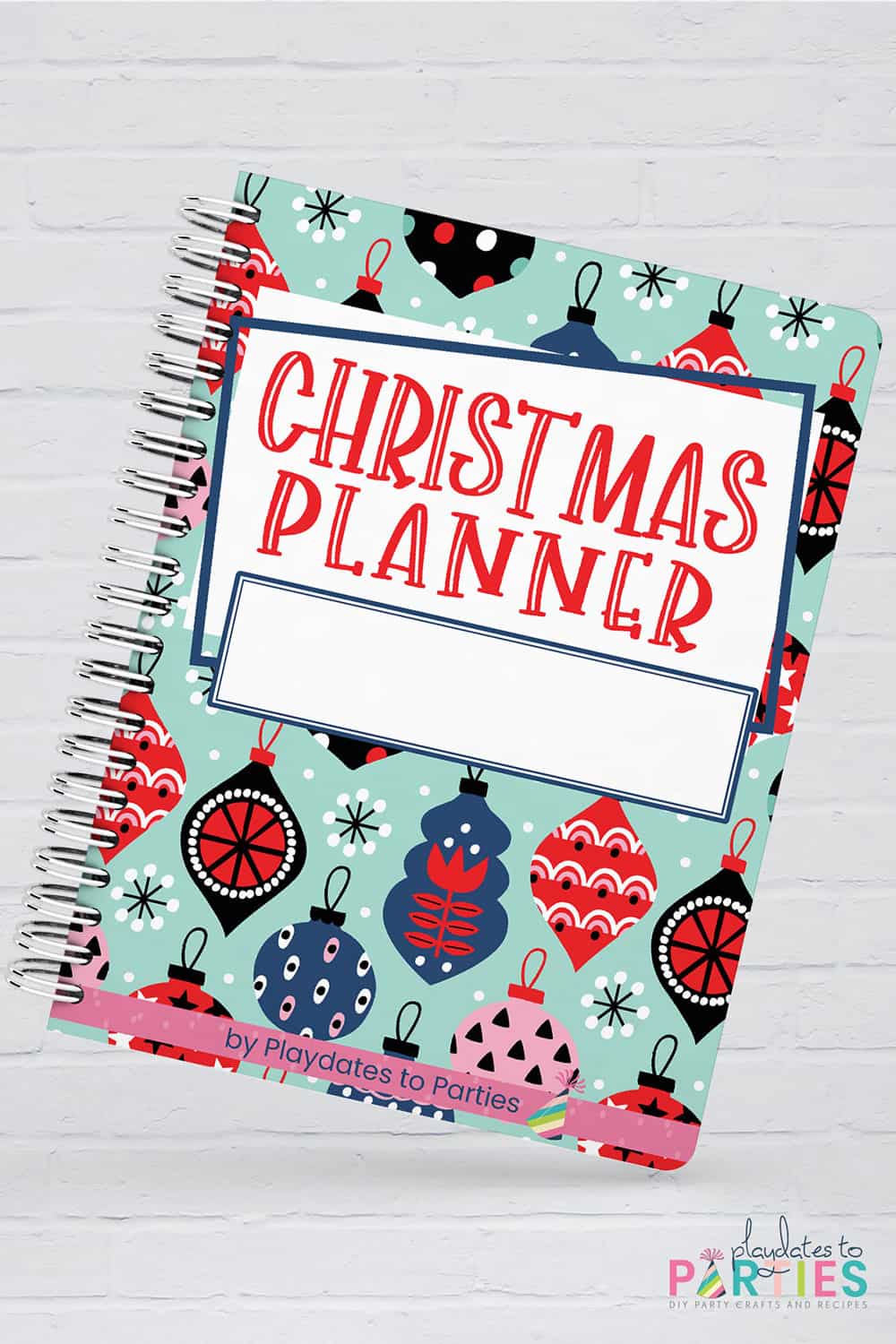 A bound copy of a Christmas planner against a white brick background.
