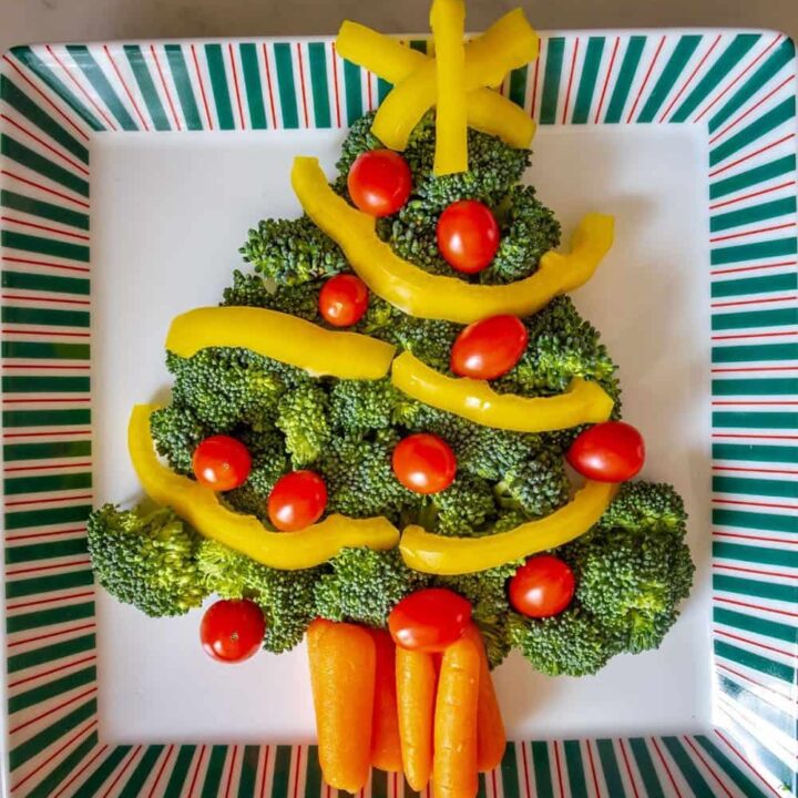 Veggies in the shape of a Christmas tree with broccoli, carrots, tomatoes, and bell pepper strips.