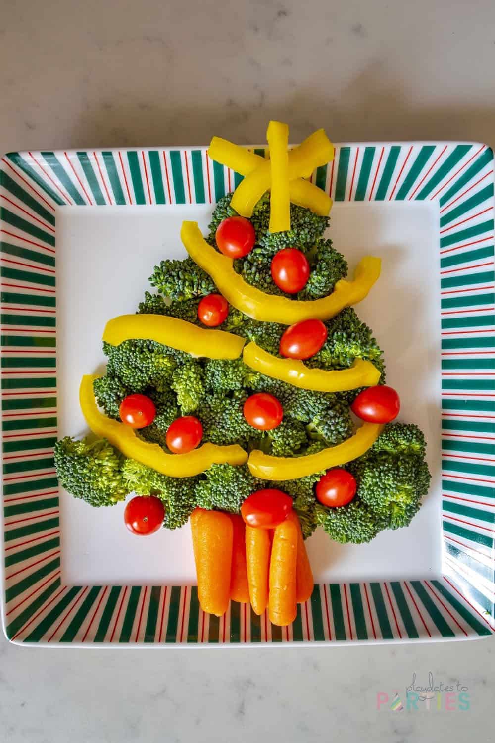 Veggies in the shape of a Christmas tree with broccoli, carrots, tomatoes, and bell pepper strips.