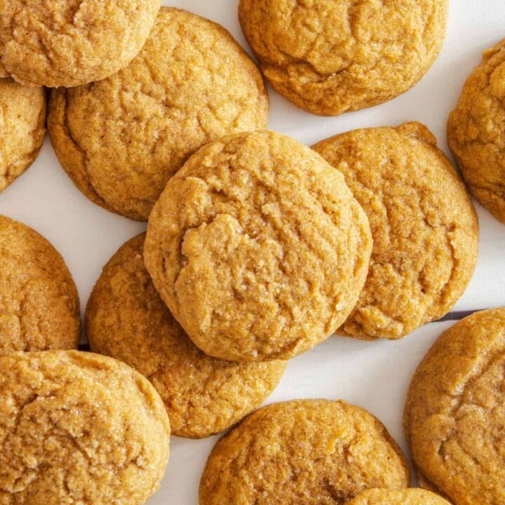 Cookies scattered and piled on a white wood surface.