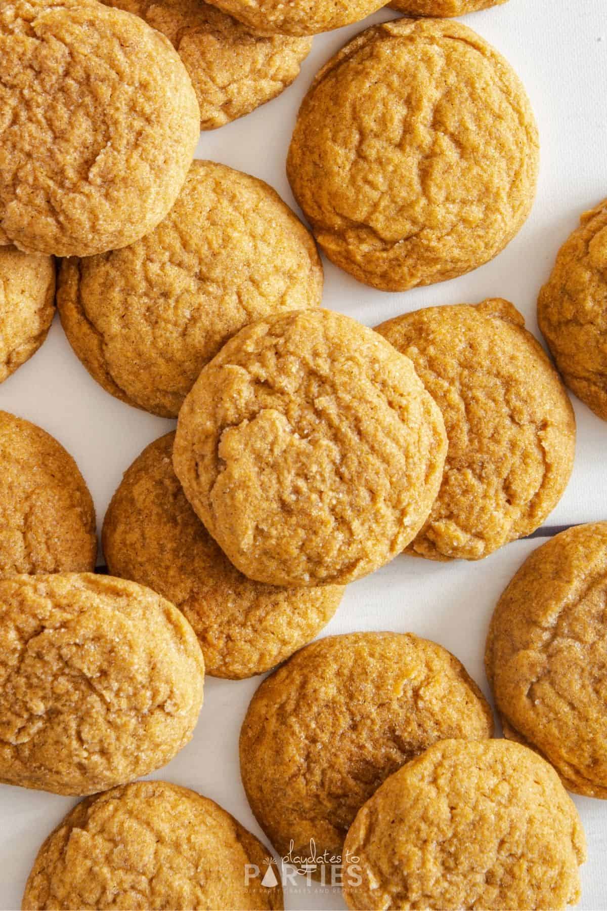 Cookies scattered and piled on a white wood surface.