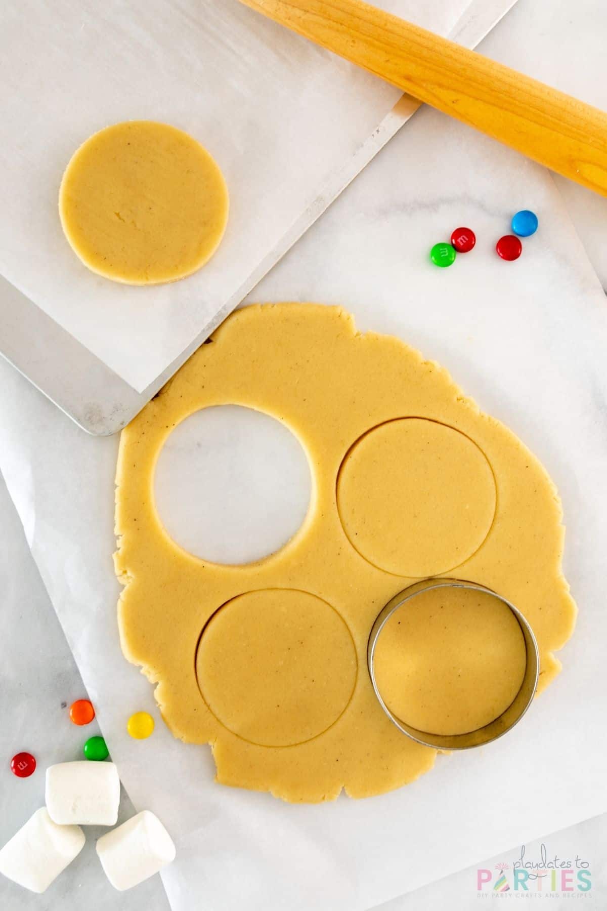 Rolled out sugar cookie dough with circles cut out by a round cookie cutter.