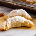 Front view of finished pecan crescent cookies on a marble surface.