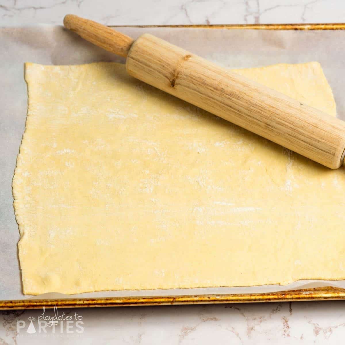 Rolling out puff pastry on a baking sheet.