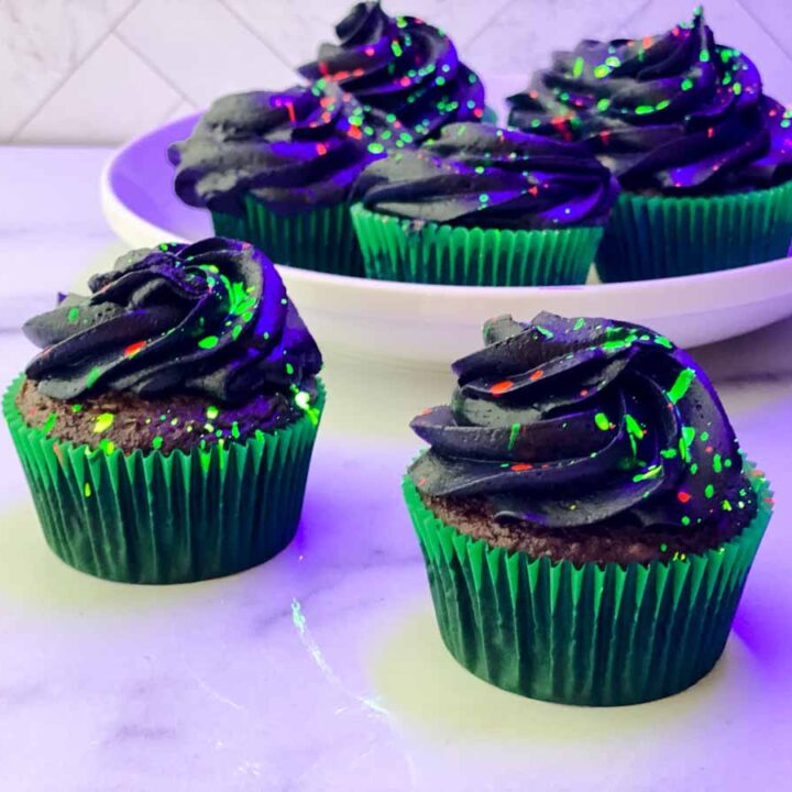 Dark cupcakes with glowing paint spatter decorations.