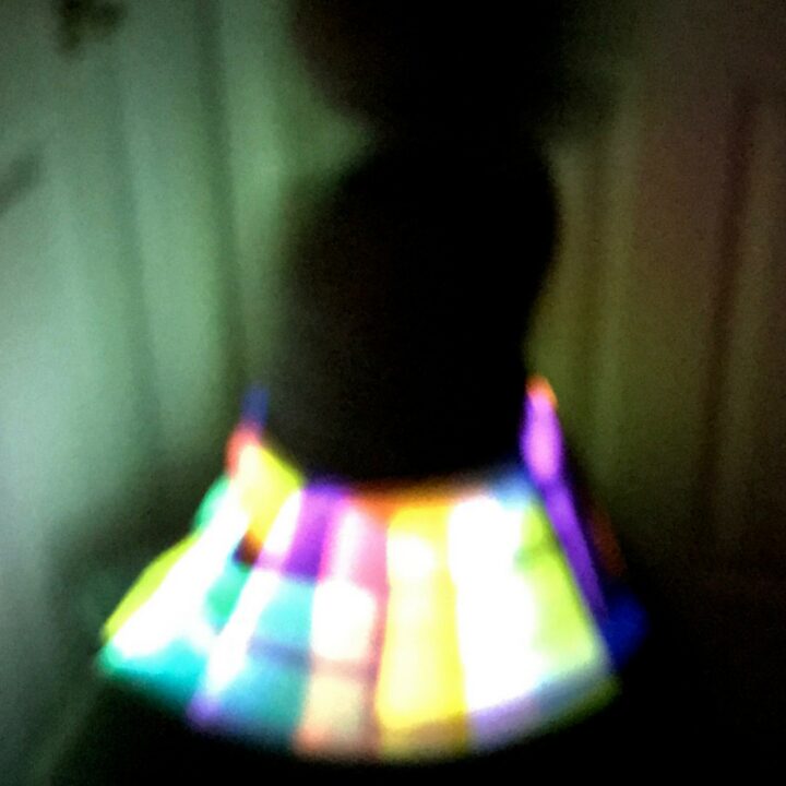 A young girl twirling in the dark with a light up skirt.