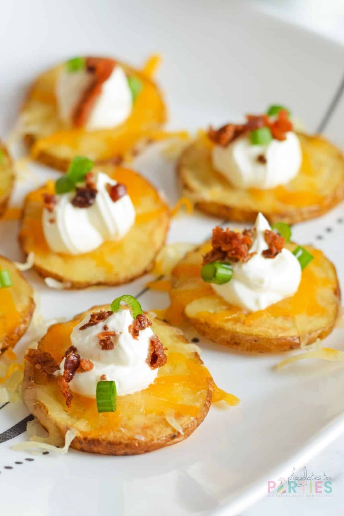 Potato slices topped with cheese, sour cream, bacon, and green onion.