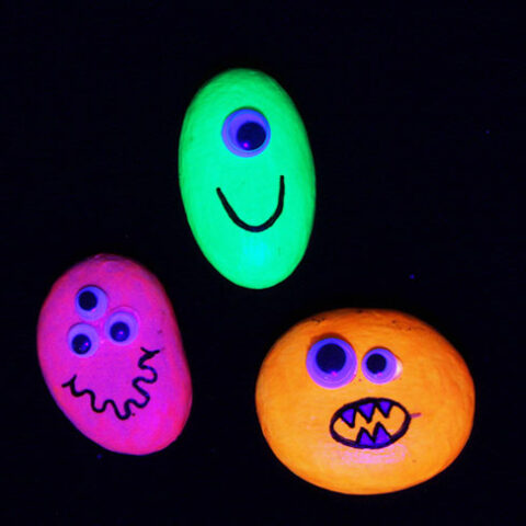 Glowing green, pink, and orange rocks with faces.