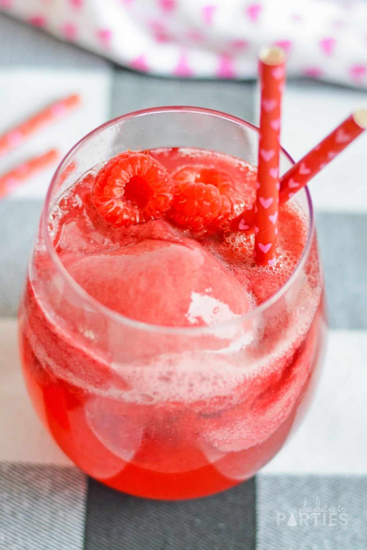 Looking into a wine glass with champagne, sorbet, and fresh raspberries.