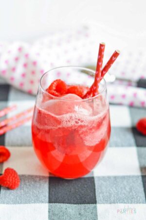 Pink champagne float with raspberries and sorbet on a checkered surface.