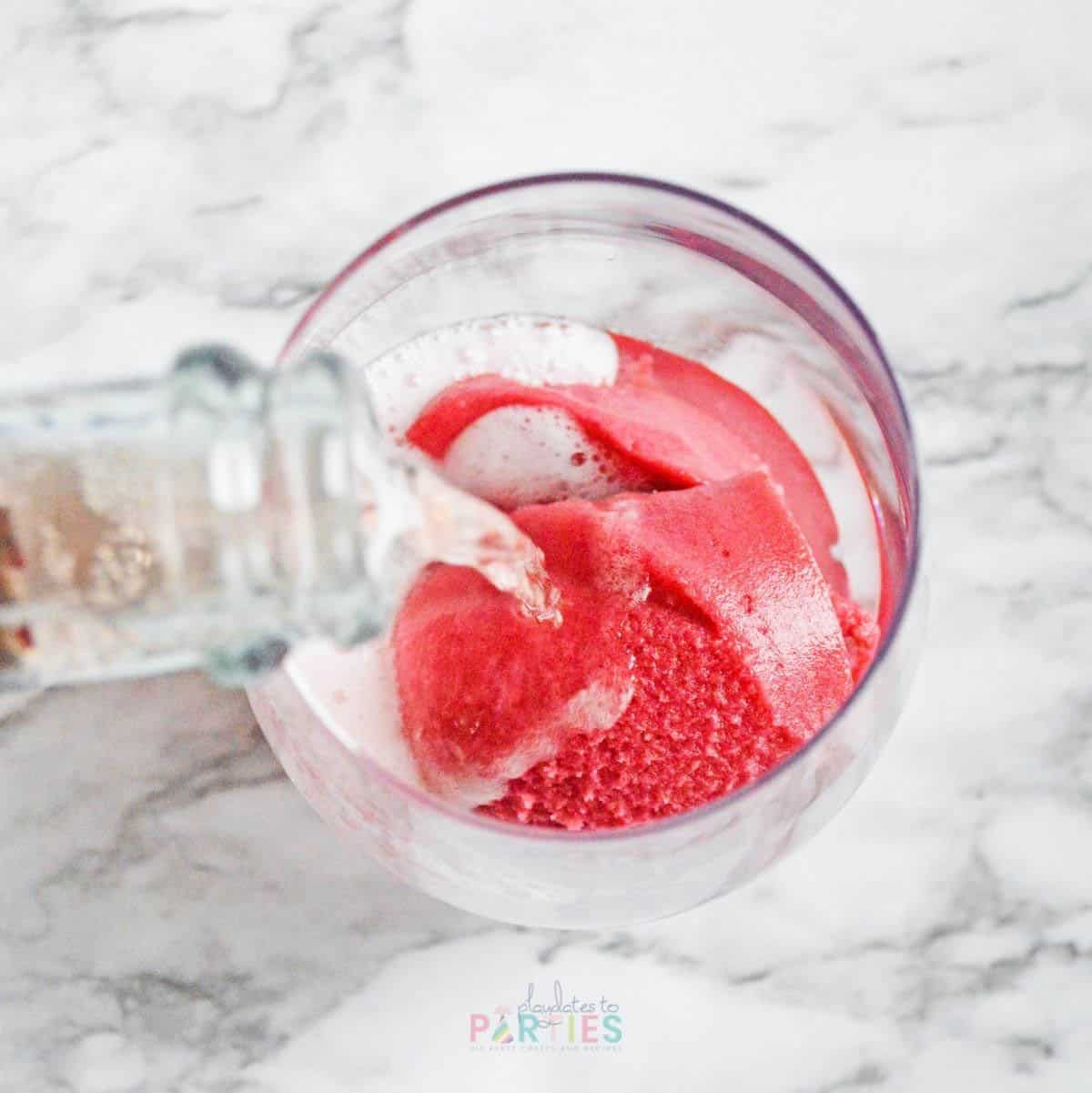 Pink champagne being poured over raspberry sorbet.