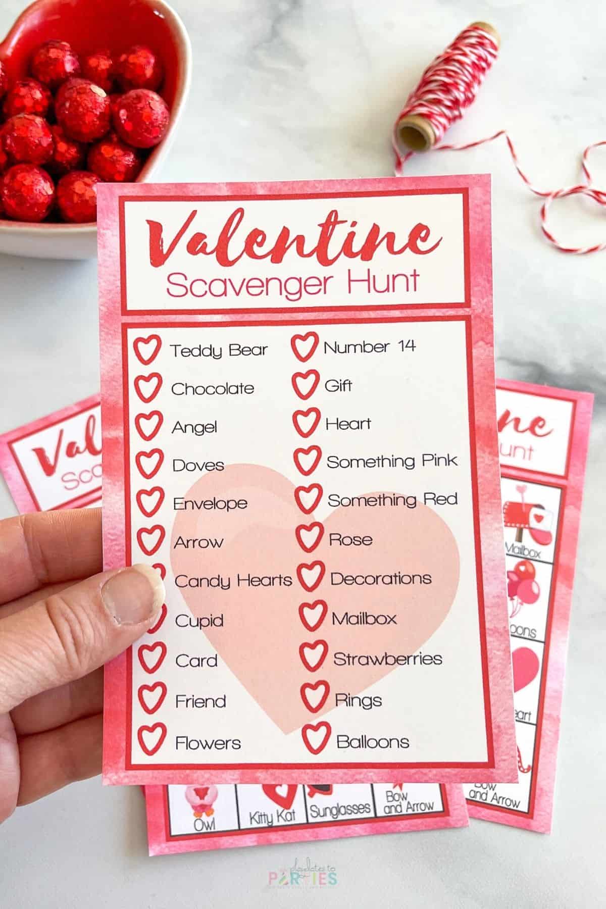 A woman's hand holidng a printable Valentine's Day Scavenger Hunt card.