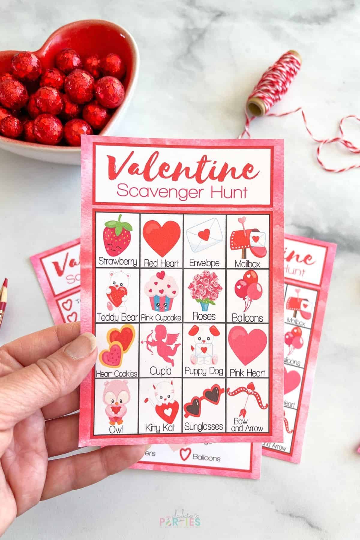 A woman's hand holding a scavenger hunt card for preschoolers.