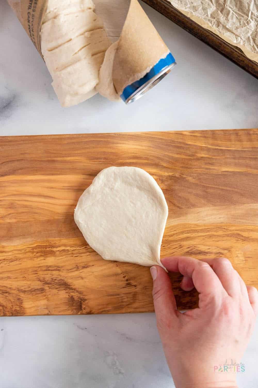 Pinching rolled dough to create the bottom point of a heart for mini heart shaped pizzas.