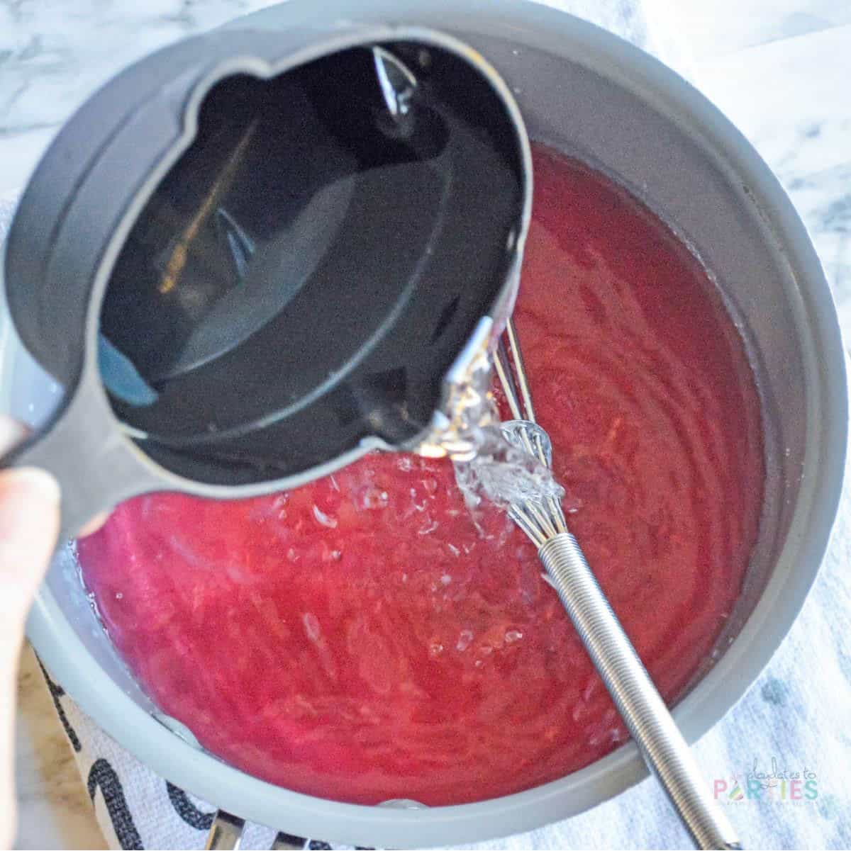 Mixing vodka into pink starburst gelatin mixture for jello shots.