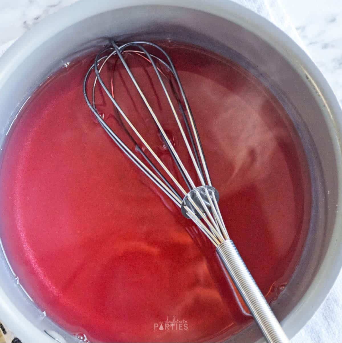 Pink starburst gelatin mixture steaming after boiling water is added.