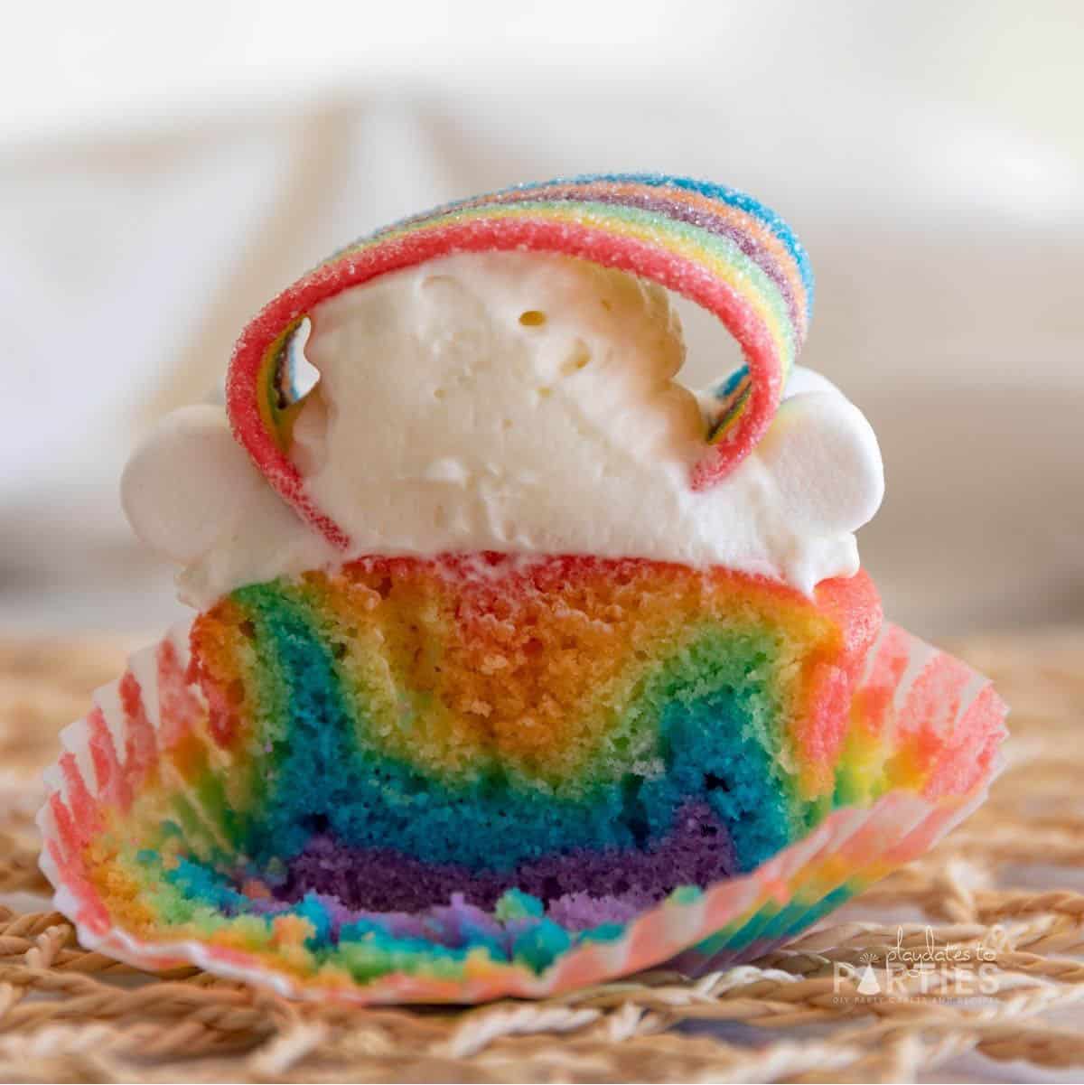 Cross section of a rainbow cupcake that shows the layers of purple, blue, green, yellow, orange, and red.