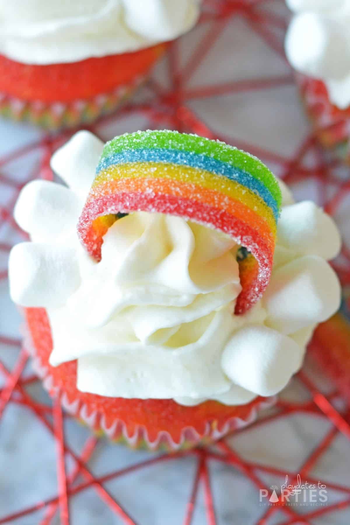 Overhead view of a cupcake with a rainbow topper and mini marshmallows.
