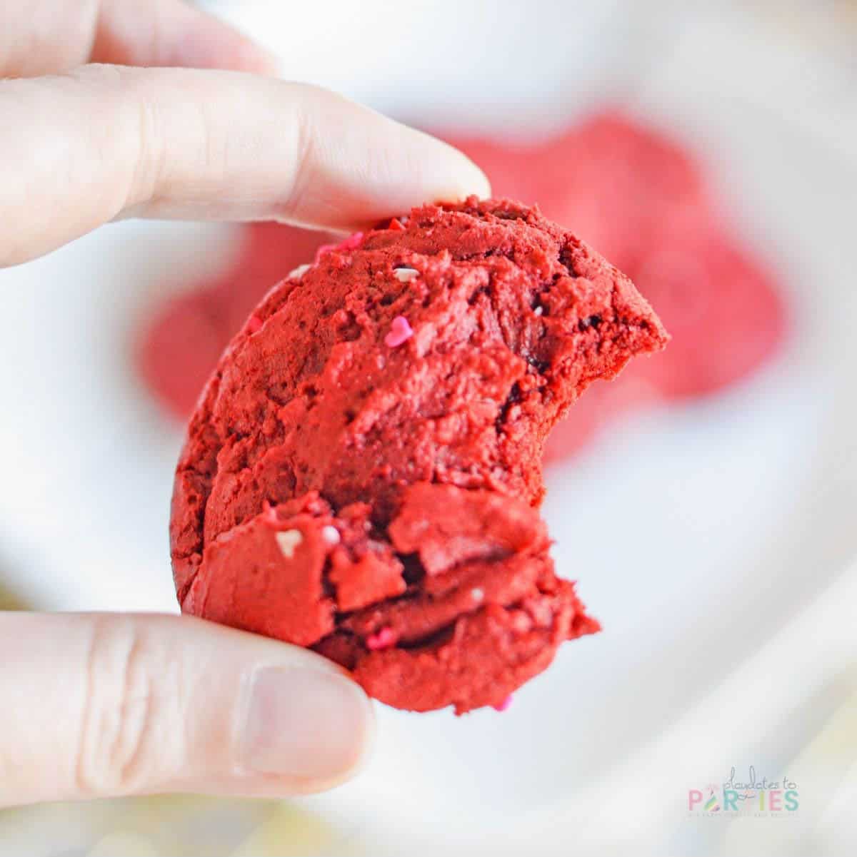A woman's hand holding a red velvet cake mix cookie.
