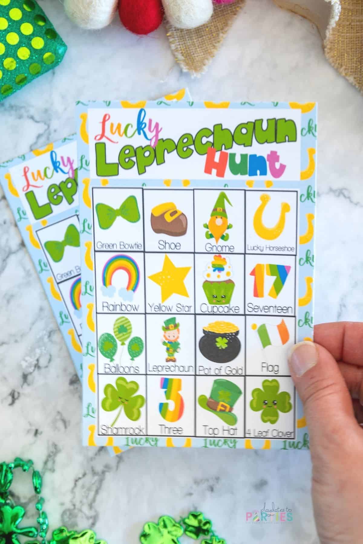 A woman's hand holding a Leprechaun scavenger hunt card made for little kids.