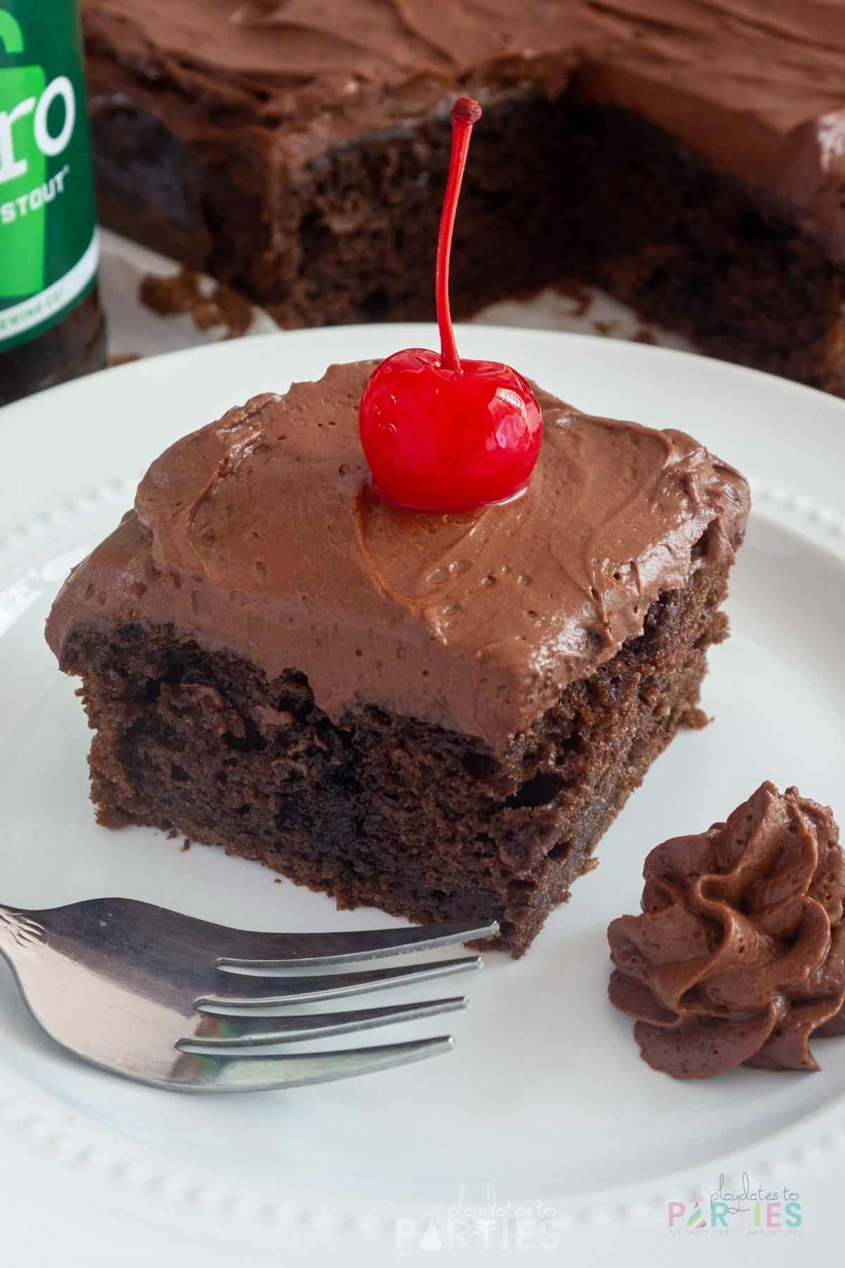 Chocolate beer cake on a white plate with a cherry on top.