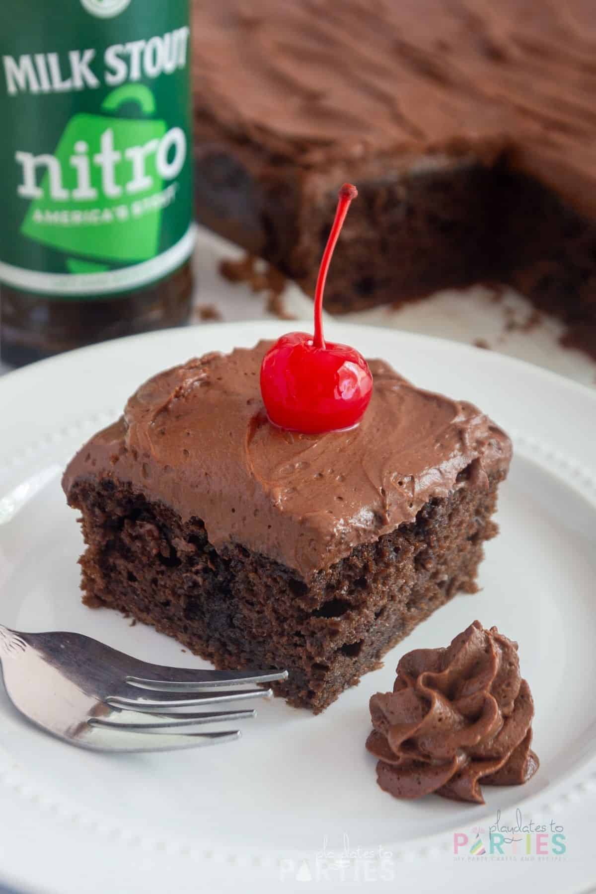A slice of chocolate sheet cake on a plate in front of a bottle of beer.