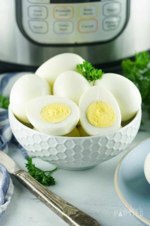 Boiled eggs in a white bowl in front of an Instant Pot.