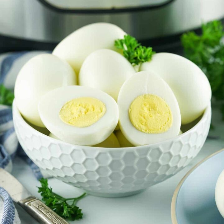 Boiled eggs in a white bowl in front of an Instant Pot.