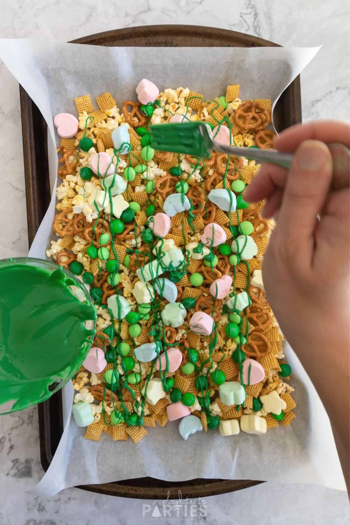 Drizzling green candy melts on Leprechaun bait snack mix.