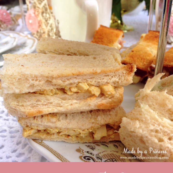 Coronation chicken finger sandwiches stacked on a plate.