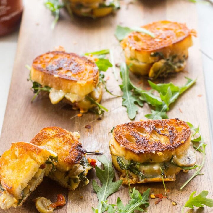 Mini gourmet grilled cheese sandwiches on a cutting board.