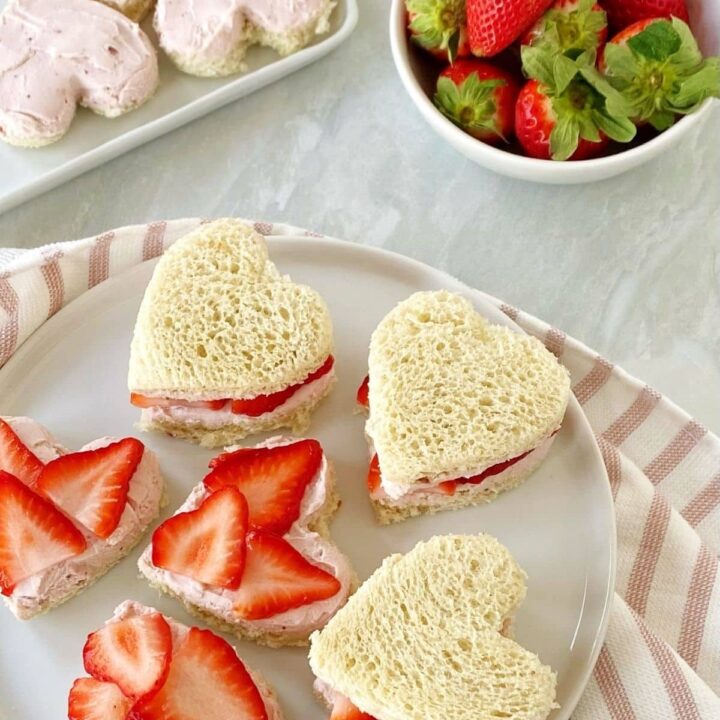 Heart shaped finger sandwiches filled with strawberries and cream cheese.