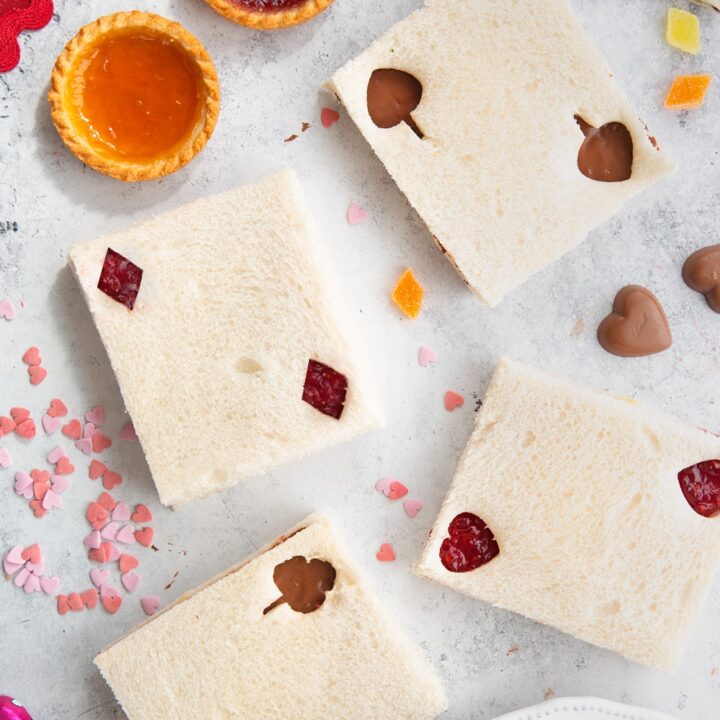 Finger sandwiches cut to look like playing cards on a white surface.