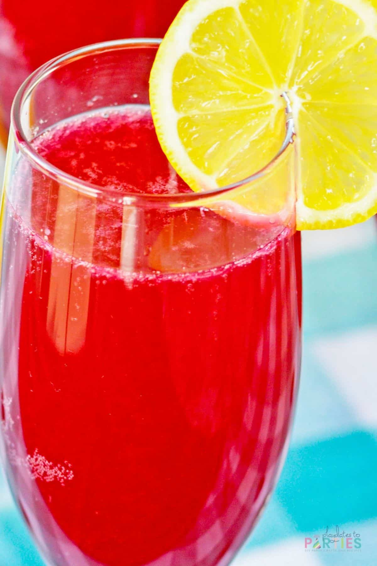 Close up of a blueberry mimosa garnished with lemon.