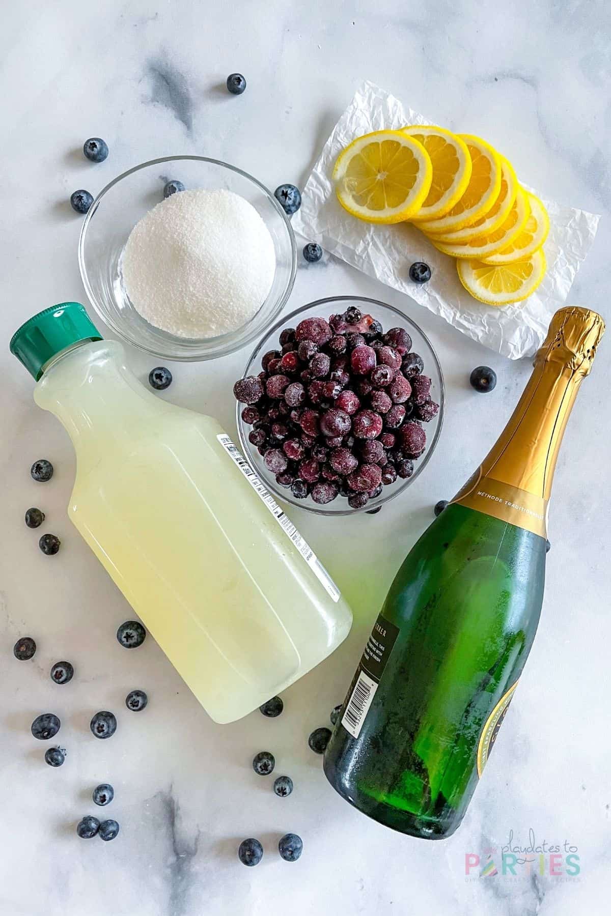 Ingredients for lemon blueberry mimosas: sugar, lemonade, blueberries, and champagne.