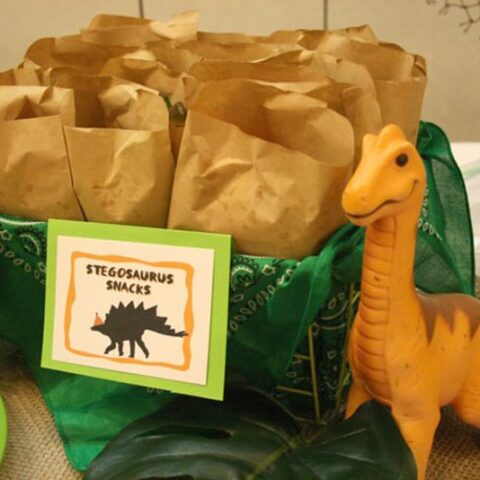 Display of brown paper bags filled with treats and a tag that says stegosaurus snacks.