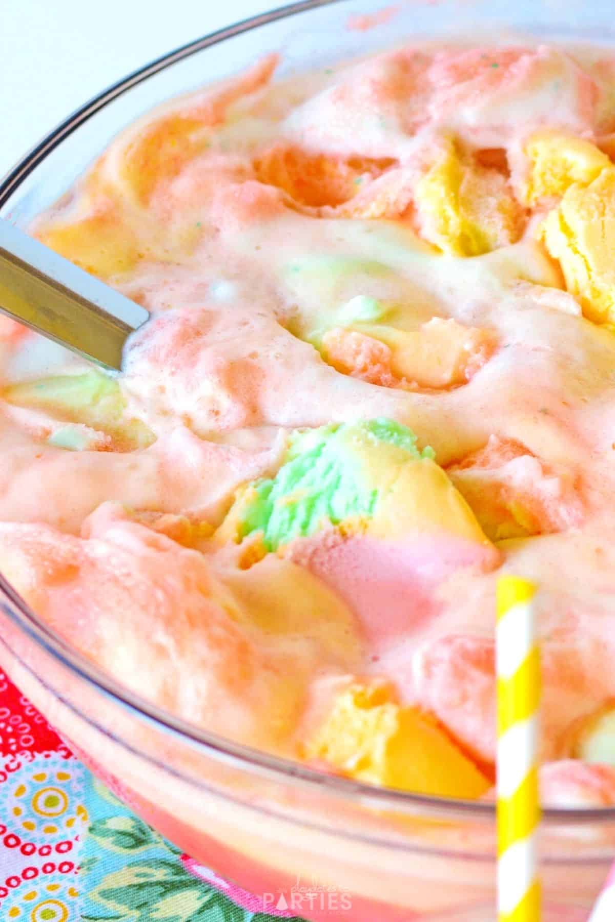 Close up of a punch bowl with frothy rainbow sherbet on top.
