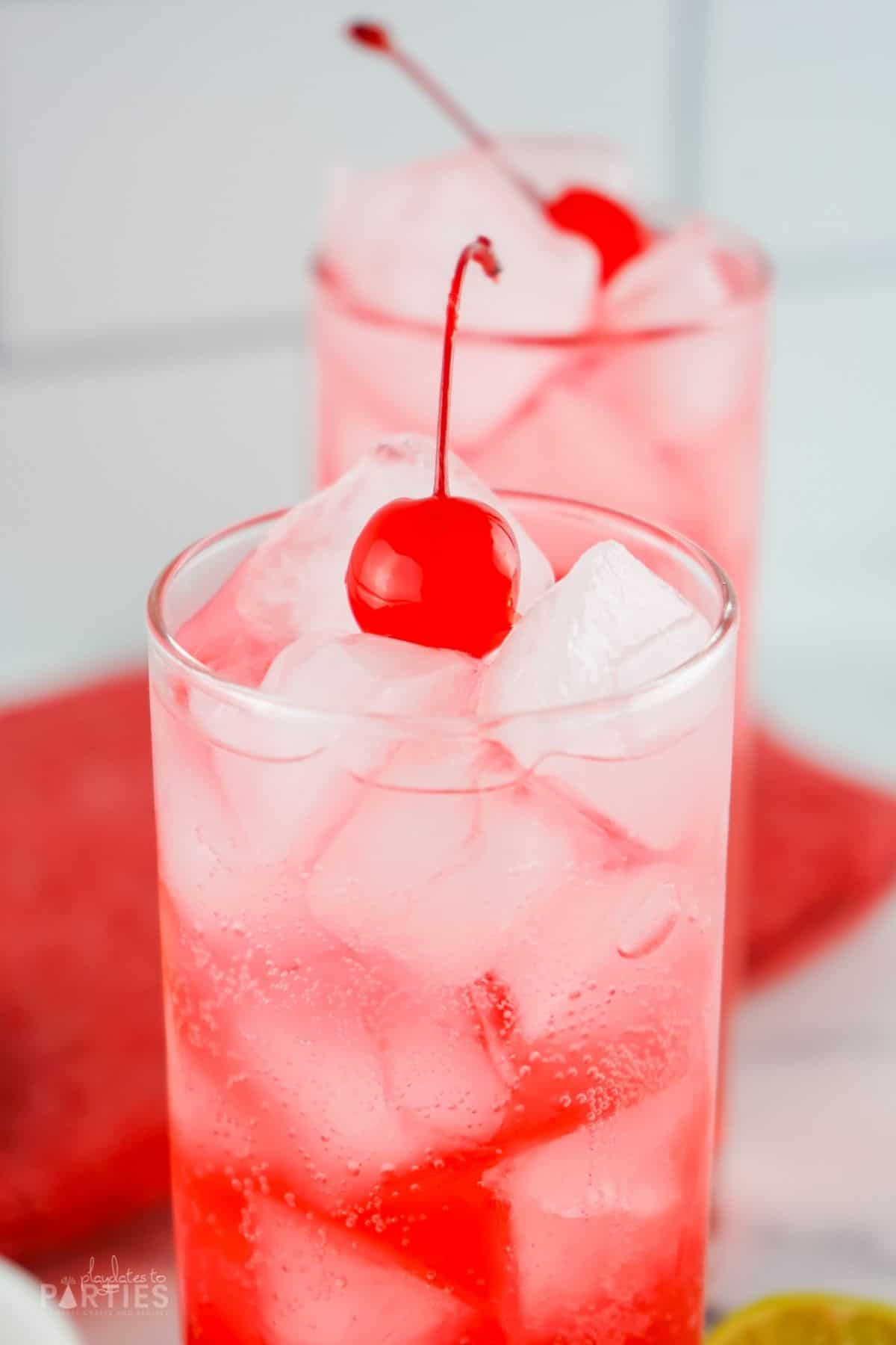 Close up of a maraschino cherry on an ice cold red drink.