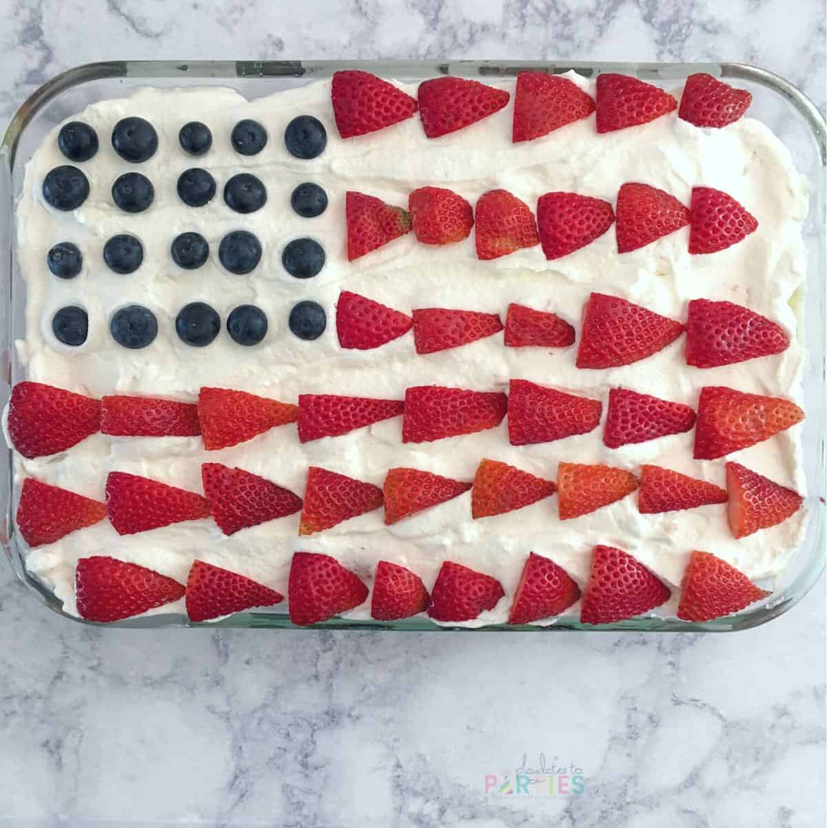 A sheet cake decorated with strawberries and blueberries to look like an American Flag cake.