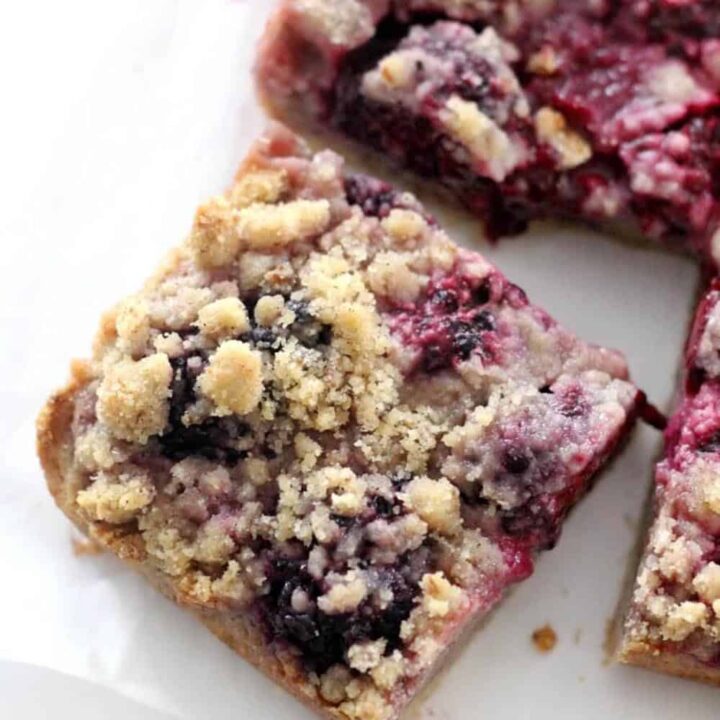 A blackberry crumb bar on a piece of white parchment paper.