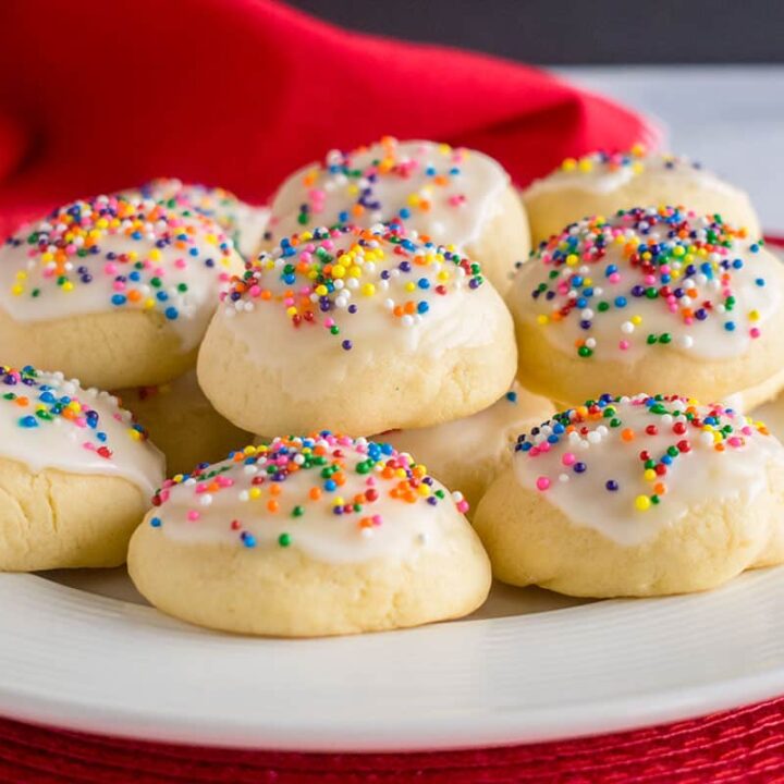 A plate of Italian cookies with glaze and rainbow sprinkles.