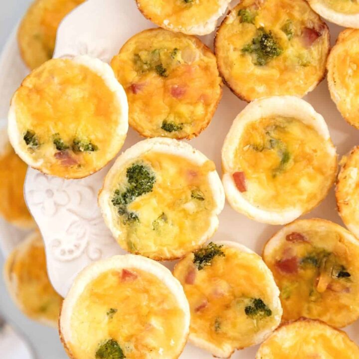 Overhead view of ham and broccoli quiche bites on a tiered white tray.